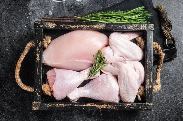 Taze çiğ tavuk eti ve tavuk parçaları - but, göğüs filetosu, kanat, but. Siyah arka plan. Üst görünüm