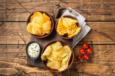 Patates cipsi çeşitleri, kırışıklık, ev yapımı, sıcak barbekü. Ahşap arka plan. Üst görünüm