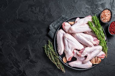 Çiğ ördek kanatları ve şifalı otlar. Siyah arka plan. Üst Manzara. Boşluğu kopyala