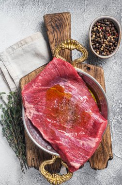 Kanat bifteği, tavada çiğ et, otlar ve zeytinyağı. Beyaz arka plan. Üst görünüm