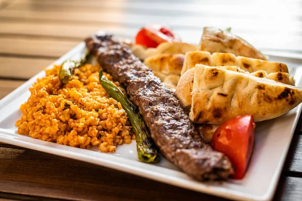 Turkish Adana kebab on a plate with marinated peppers, bread and rice pilaf. Top view — Stock Photo, Image