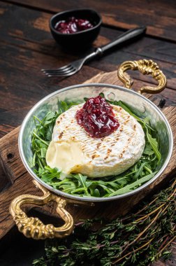 Kızılcık soslu kamembert peyniri ve tavada roka salatası ile süslenmiş. Ahşap arka plan. Üst görünüm