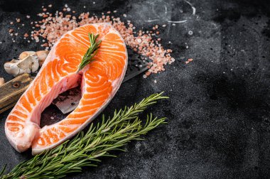 Et satırıyla kasap masasında çiğ somon balığı bifteği. Siyah arka plan. Üst Manzara. Boşluğu kopyala