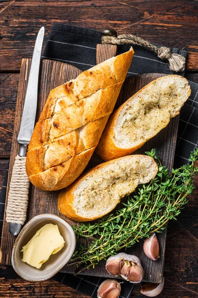 Toasted Garlic bread with herbs and butter on wooden cutting board. Wooden background. Top view — Stock Photo, Image
