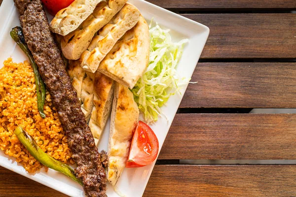 Traditional Turkish Adana kebab or kebap meat food with marinated peppers, bread and rice pilaf. Top view. Copy space — Stock Photo, Image