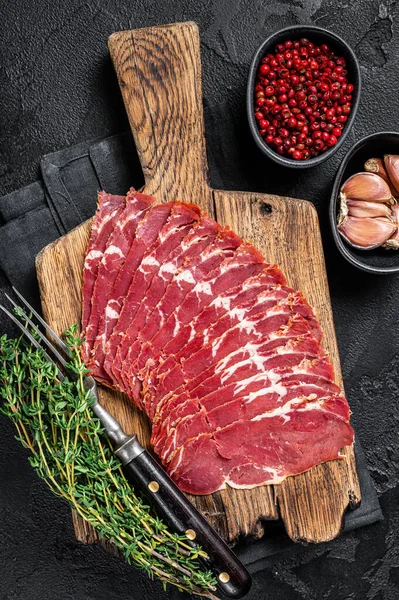 Aufgeschnittener türkischer Speck Pastrami, gebratenes Rindfleisch. Schwarzer Hintergrund. Ansicht von oben — Stockfoto