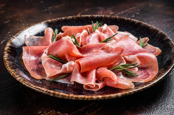 Bir dilim prosciutto crudo parma ya da jamon serrano ve biberiye. Karanlık arka plan. Üst görünüm.
