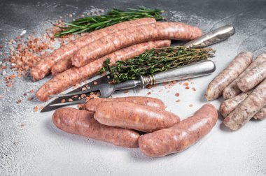 Raw Sausages variation - Beef, pork, lamb and chicken meat on a butcher table with rosemary and thyme. White background. Top view.