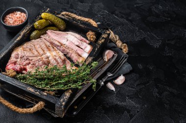 Roasted on grill Pork steaks from neck meat in wooden tray with herbs. Black background. Top view. Copy space.