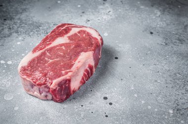 Çiğ kaburga bifteği, kasap tahtasının üzerinde mermer et. Gri arka plan. Üst Manzara. Boşluğu kopyala.