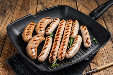 Grilled homemade sausages with Beef, pork, lamb and chicken mince meat in a grill skillet. Wooden background. Top view.