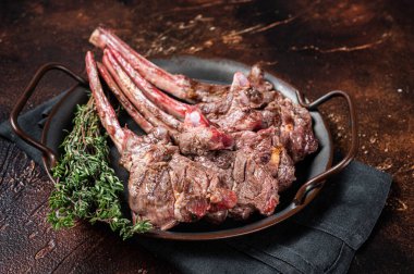 BBQ Grilled lamb chop steak, mutton rib cutlet in steel tray with thyme. Dark background. Top view.