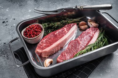 Çiğ sığır filetosu ya da tepside otlu biftek. Gri arka plan. Üst görünüm.