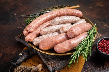 Assorted raw homemade sausages with Beef, pork, lamb and chicken meat on a plate. Dark background. Top view.