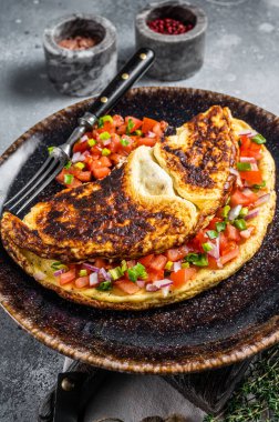 Bir tabakta domates, soğan ve otla doldurulmuş yumurta omleti. Gri arka plan. Üst görünüm.