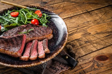 BBQ Grilled cup rump beef meat steak in plate with vegetable salad. Wooden background. Top view. Copy space.