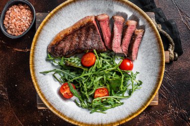 Biftekli ızgara sığır eti ve sebze salatası. Karanlık arka plan. Üst görünüm.