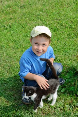 Yeşil çimenlerin üzerinde yavru kedi ile çocuk