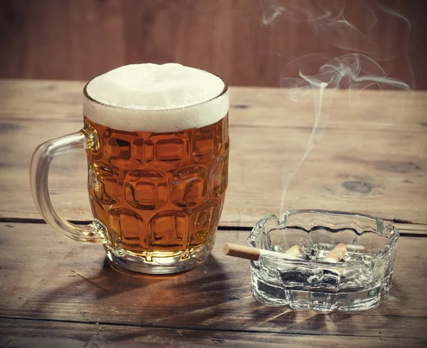 Pint of Beer and a lit cigarett — Stock Photo, Image