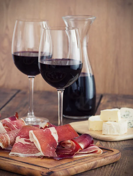 Sliced prosciutto with red wine and olives — Stock Photo, Image