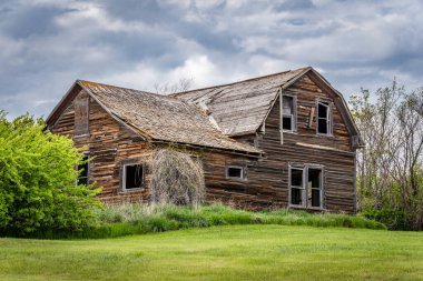 Blue sky over a stately, old, abandoned home on the prairies of Saskatchewan