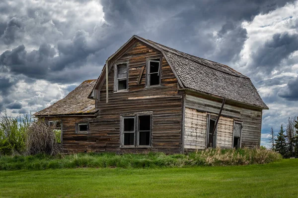 Stormy skies over a stately, old, abandoned home on the prairies of Saskatchewan