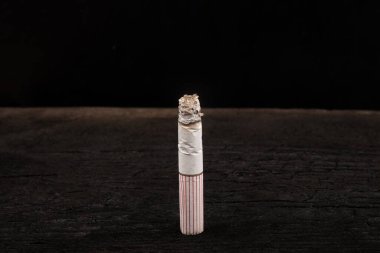 Siyah arka planda sigara yakmak, sigara içmek, kötü alışkanlık.