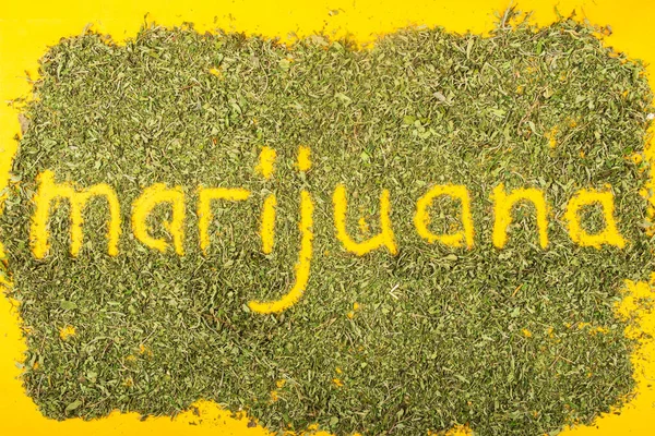 緑の麻の葉の間の単語マリファナの碑文 — ストック写真
