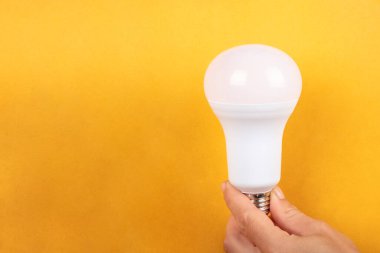 Elektrik enerjisi tasarrufu öncülüğünde sarı arkaplan ve telif alanı.