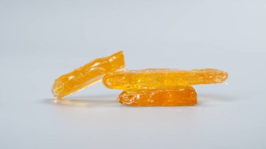 Gri arka planda yüksek oranda esrar mumu, altın gibi temiz marihuana parçaları konsantrasyonu.