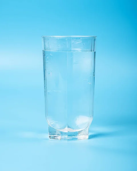 clean water in a glass beaker closeup on a blue background.