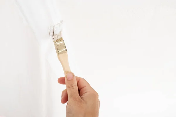 tint the skirting board with a brush, painting white color plinth.