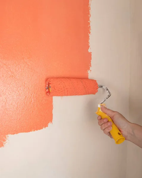 painting the wall with orange paint closeup, cosmetic repairs in the house.