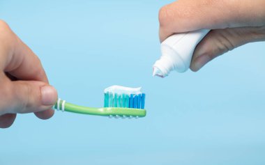 toothpaste is applied to the toothbrush,tooth brushing in hand on blue background.
