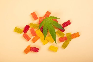 thc jelly candies, cannabis sweets drugs and green leaf on yellow background. clipart