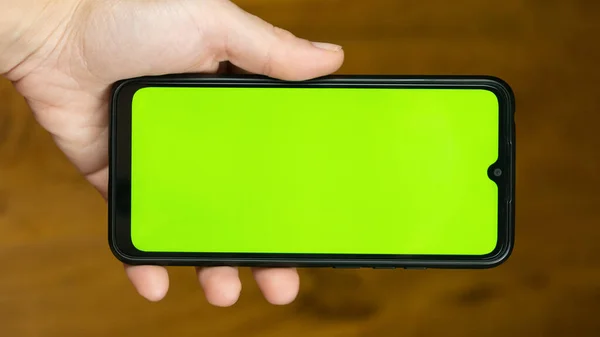 mobile phone with green chroma key on touch screen in woman hands.