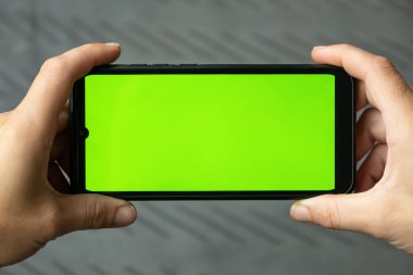 mobile phone with green chroma key on touch screen in woman hands...