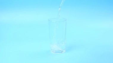 water pouring into the glass on a blue background. High quality FullHD footage