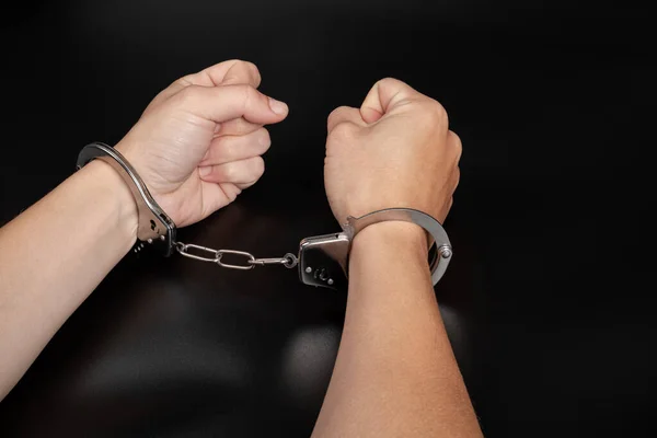 handcuffs arrest, detention of a woman for a crime on dark background.