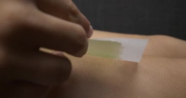 woman covering her leg with a wax strip for depilation. High quality 4k footage