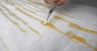 golden dabs of cannabis extract resin and smoking scraper parchment paper. High quality 4k footage