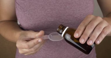 hand pour a bottle of medicinal syrup into a spoon High quality 4k footage