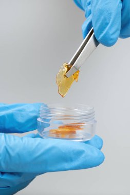 high thc resin, hand get cannabis wax with tweezers in box.