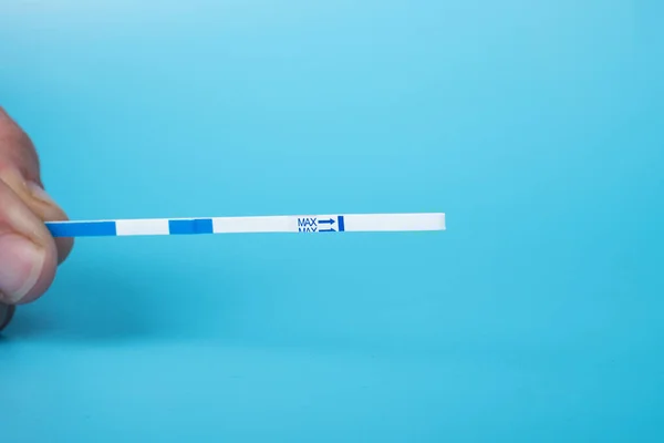 pregnancy medical test closeup on a blue background.