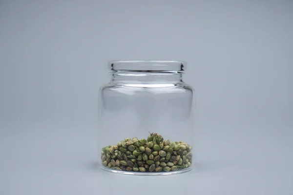 filling a glass container with cannabis seeds, cannabis breeding grow hemp seeds.