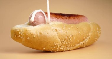 Sosisli sandviçe mayonez sosu dök. Ekmek ve sosisli fast food. Yüksek kalite 4k görüntü