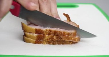 Bir el tütsülenmiş göğüs etini bıçakla yakın plan kesiyor, dilimlenmiş domuz eti. Yüksek kalite 4k görüntü