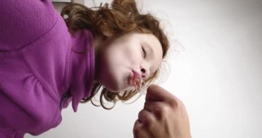 Küçük kız kaşıktan öksürük şurubu içiyor, annesi çocuğu tedavi ediyor. Yüksek kalite 4k görüntü