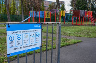 Prestatyn, UK: Dec 14, 2021: Coronation Gardens is a public park, named in 1911 to commemorate the coronation of King George V and Queen Mary. A sign gives covid advice beside the childrens play area