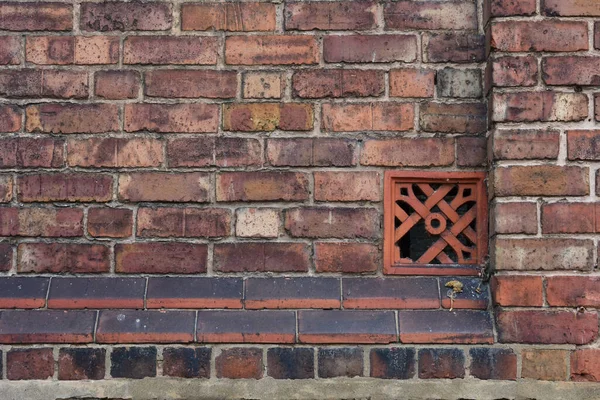 Red brick wall with a broken ventilation brick